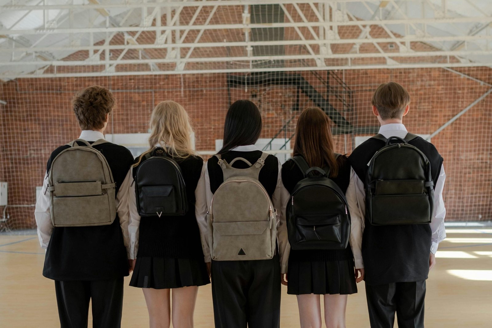 Premium CBSE Running School for Sale – Investor Opportunity A group of five students in uniform stand indoors with backpacks, facing away.
